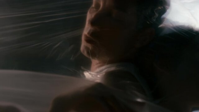 Caucasian young adults trapped beneath tight plastic film, moving slowly. Clip serves environmental pollution campaigns, suffocation concepts, and mental health awareness projects