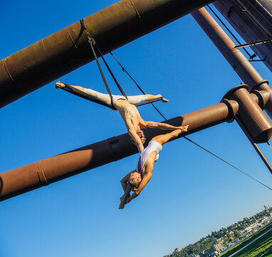 Two acrobats performing aerial straps act outdoors in Seattle