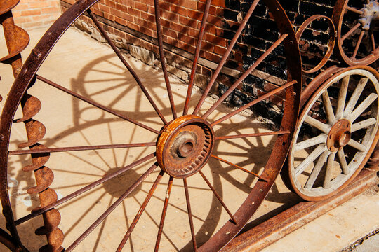 Rusty iron wheels casting shadows on concrete by brick wall