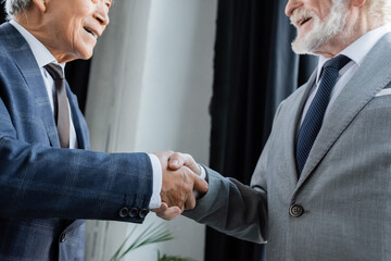 Seasoned multicultural executives seal a partnership with a confident handshake © LIGHTFIELD STUDIOS