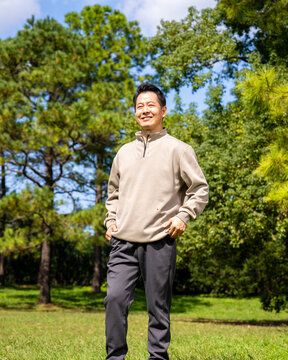 Outdoor portrait of friendly middle age asian male, relaxed casual outfit on sunny day
