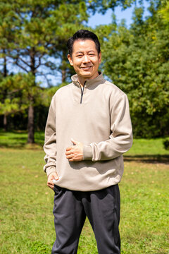 Outdoor portrait of friendly middle age asian male, relaxed casual outfit on sunny day