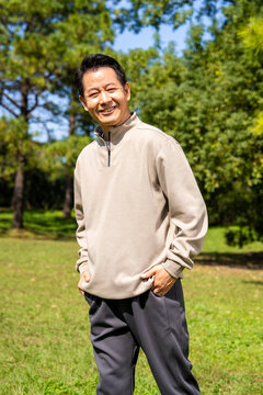 Outdoor portrait of friendly middle age asian male, relaxed casual outfit on sunny day