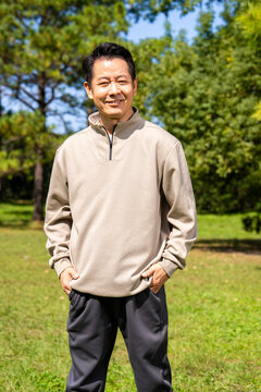 Outdoor portrait of friendly middle age asian male, relaxed casual outfit on sunny day
