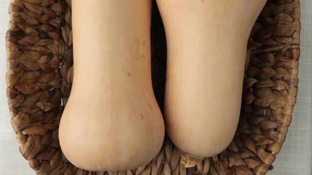 Fresh butternut squash resting in woven wicker basket