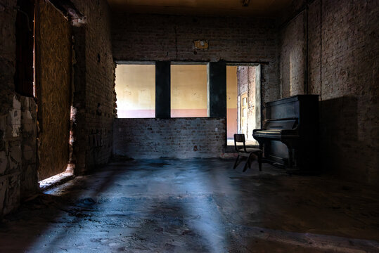 Old broken piano and chair in abandoned ruined mansion. Haunted house interior