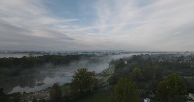 Aerial rise over morning fog on the river and weir in Wrocław
