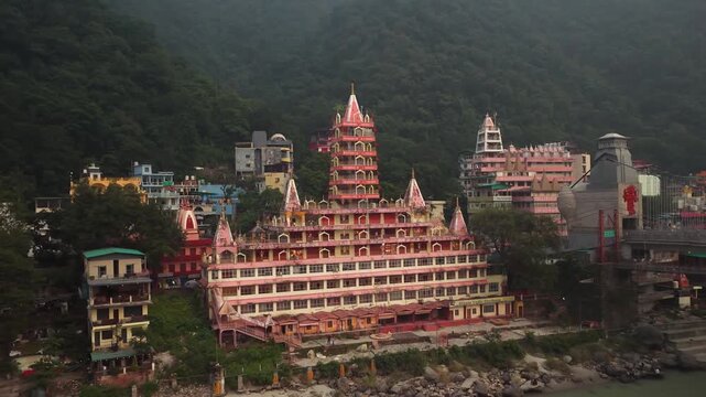 Pull in drone view of the Trayambakeshwar Temple (also known as the Tera Manzil Temple), a famous 13-story multi-deity temple located on the banks of the Ganges River near Lakshman Jhula in Rishikesh,