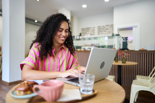 Person working remotely on laptop in cafe smiling