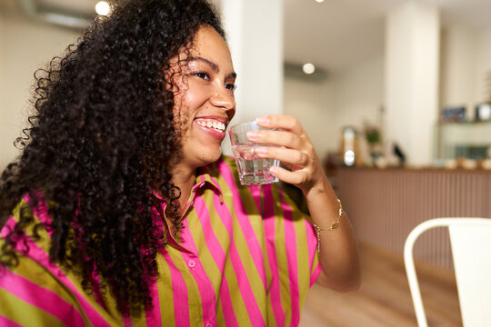 Person smiling and drinking water, promoting hydration and wellness