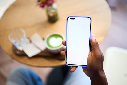 Holding smartphone with blank screen in cafe