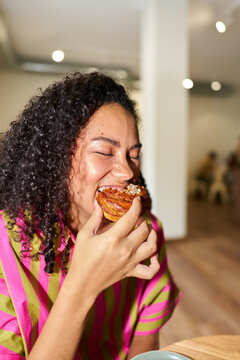 Person enjoying cinnamon bun snack in a cafe