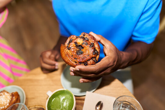 Hands holding sweet pastry at breakfast table