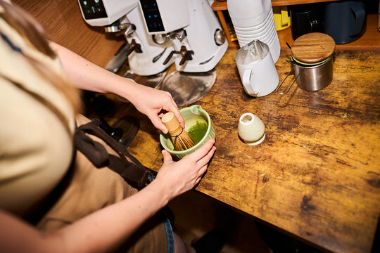 Preparing matcha green tea with a bamboo whisk in a cafe