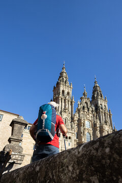 Low angle shot of a pilgrim with backpack looking at santiago de compostela cathedral from obradoiro square copy space