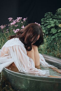 Calm woman in white dress sit in bath