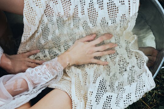 Anonymous woman hands touch delicate lace fabric in water