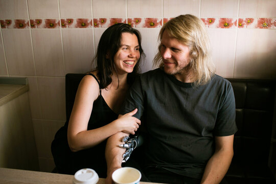 Happy couple laughing, sitting together and drinking coffee at home