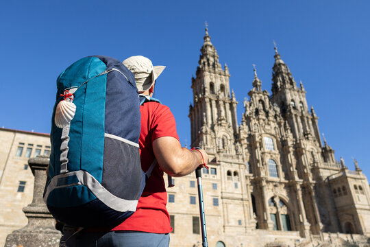 pilgrim with backpack looking at santiago de compostela cathedral from obradoiro square