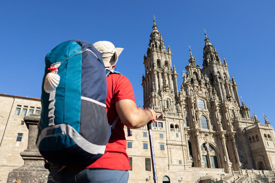 blurred pilgrim in foreground looking at santiago de compostela cathedral in background