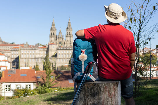 pilgrim sitting next to backpack looking at santiago de compostela cathedral