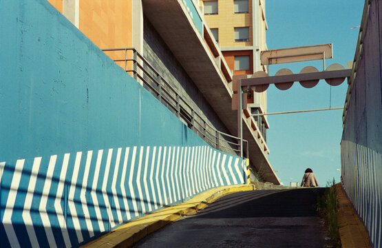 Woman Walks Up a Blue-Walled Ramp