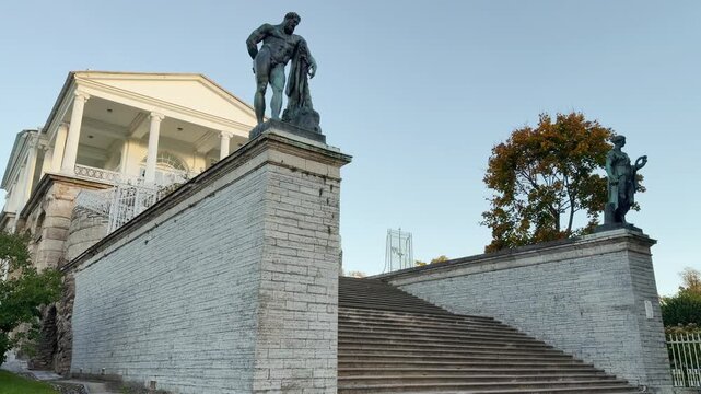 Statues stand on grand stone stairs at Cameron Gallery in Catherine Park, Pushkin, Saint Petersburg. The majestic architecture inspires a peaceful awe.