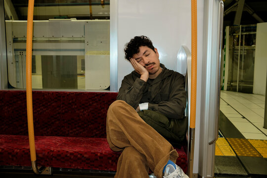 Tired Man Resting on Train Seat in Japan