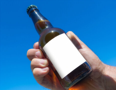 Amber beer bottle mockup with a blank white label held against blue sky