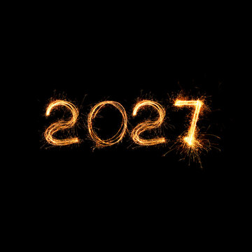 Sparkling Happy New Year 2027 text written with sparklers fireworks isolated on black background. Bright golden light burning digits 2027 for holiday celebration card, banner and creative design.