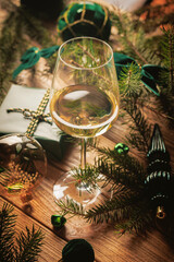 White wine glass surrounded by Christmas gifts evergreen branches and ornaments creating an elegant festive table setting for holiday dining restaurant promotion and greetings © svittlana