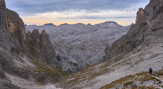 Landscape as seen from route Alta Via 2. Pale di San Martino Plateau, Cima Fradusta and Fradusta Glacier in background. Paneveggio Pale di San Martino park. Rocky moon-like plateau. Hiker in the trail