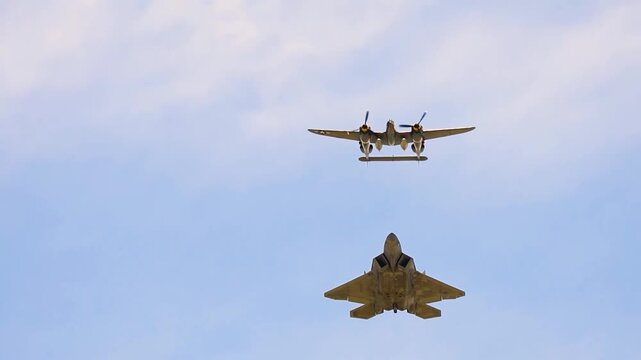 Modern stealth fighter jet and historic twin-engine warplane flying together in a blue sky.