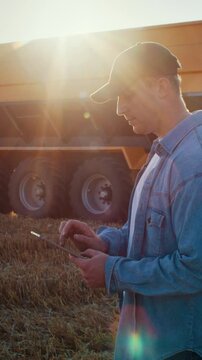 Farmer controls data by tablet as tractor trailer drives past