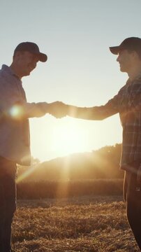 Farmers seal business partnership with handshake in sunset field