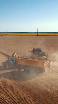 Harvest machines move through dusty field during grain collection