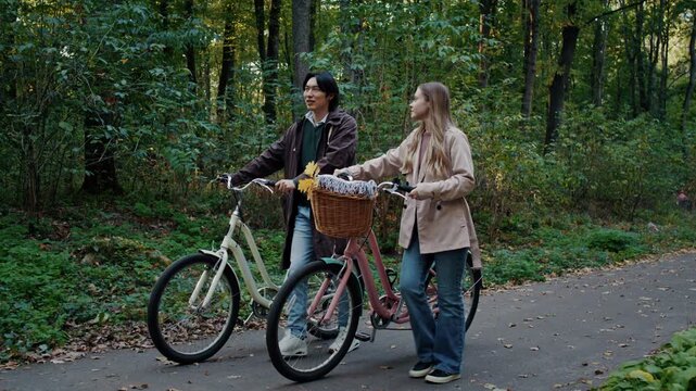 Young couple strolls with bicycles through green woodland path
