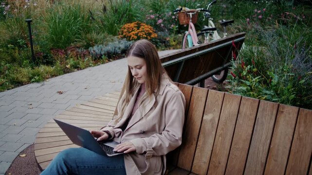 Lady freelancer types on laptop during remote work in autumn park