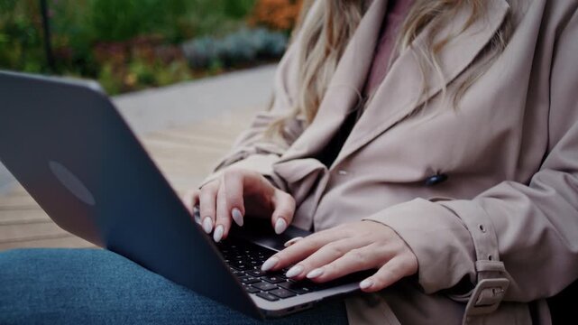 Woman hands type on laptop keyboard during busy moment in park