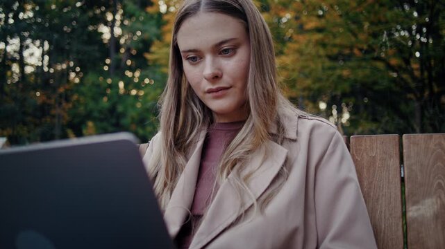Focused woman looks at laptop screen while working outdoors