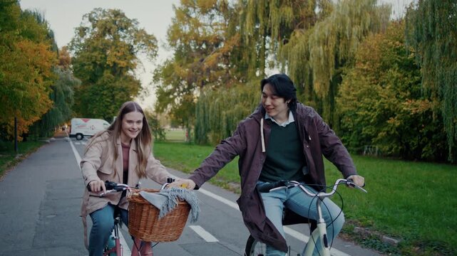 Man takes autumn leaf from bike basket while cycling with woman