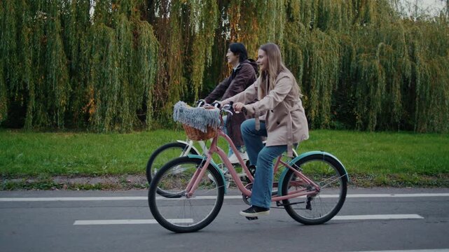 Couple rides bicycles side by side along autumn park road
