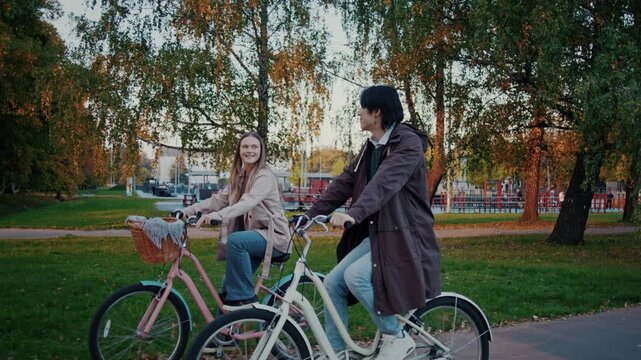 Couple cycles side by side through colorful autumn city park