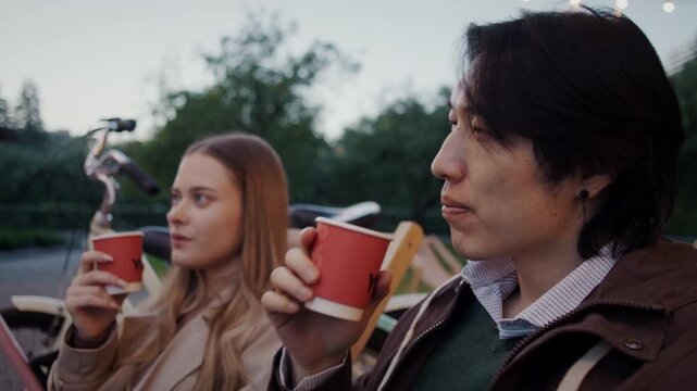 Couple drinks from red cups while relaxing near parked bicycles