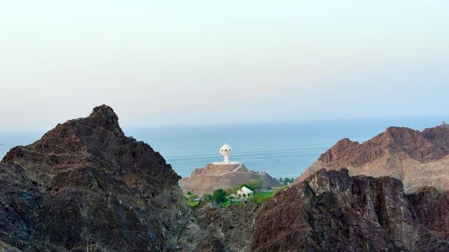 Scenic views of Muttrah in Muscat, Oman, featuring rocky mountains, green parks, traditional buildings, and coastal harbor views. Muscat, Oman - October &lrm;21, &lrm;2026.