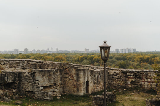 Weathered walls at Belgrade Fortress overlook autumn trees and a distant skyline. Historic masonry beside modern development illustrates heritage and urban change.