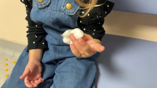 A child displays a fingertip covered with cotton after blood sampling, pediatric healthcare, medical visit, patient aftercare.