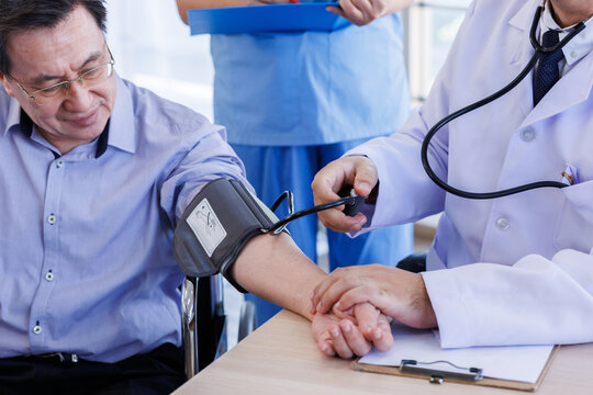 Male doctor advising with positive  to Asian a man Mid-adult a patient checking blood pressure rate and discussing health treatment sitting in the office at the desk. Medicine and health care concept.
