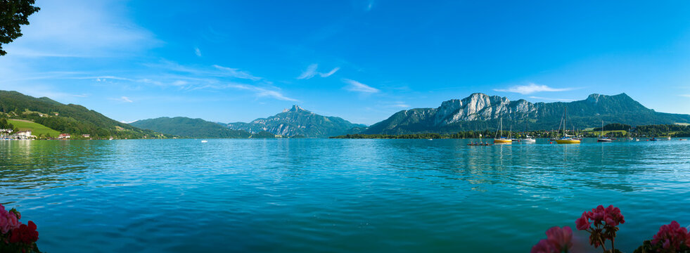 Panoramic view over turquoise Mondsee lake with Schafberg mountain and sailboats in Salzkammergut Austria