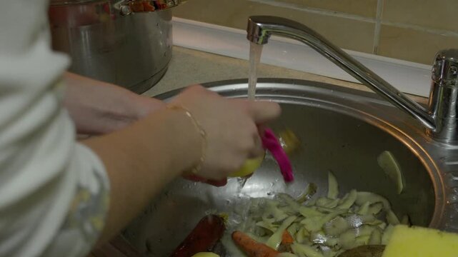 Hands Peeling Potato Over Kitchen Sink During Home Meal Preparation